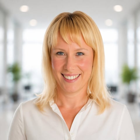Portrait of a smiling blonde woman wearing a white blouse in a bright modern office setting